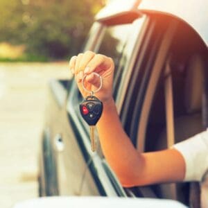 A person holding keys out of their car window.